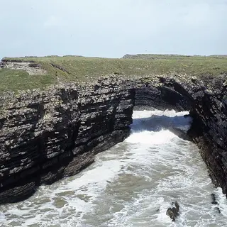 The sea arch at the Bridges of Ross, with the waves running in under it