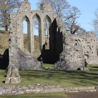 The tall lancet windows of the ruined church at Inch Abbey, with low walls in the grass in front