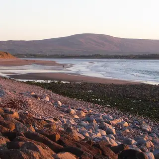 The stony upper shore of Strandhill beach in the evening light, with the hills behind