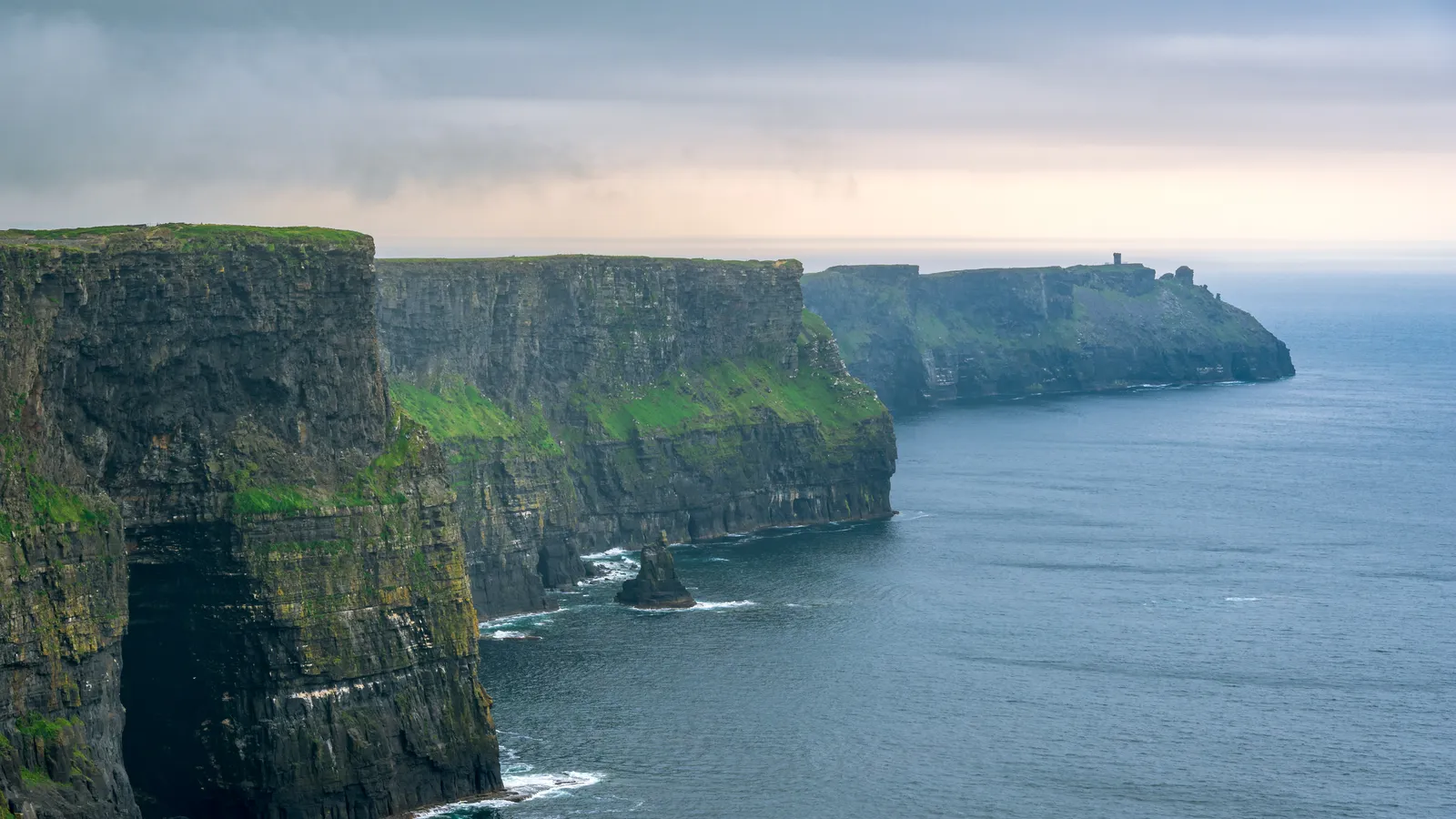 The Cliffs of Moher dropping to the Atlantic, with the clifftop path along the green edge