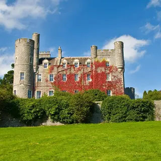 The turreted granite castle in Castlewellan Forest Park, red creeper on its walls, above a lawn