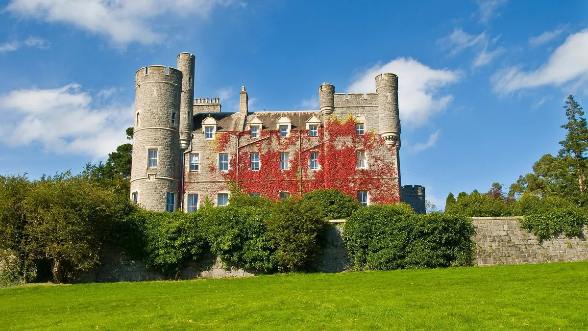 The turreted granite castle in Castlewellan Forest Park, red creeper on its walls, above a lawn