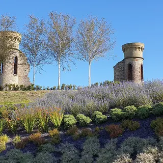 Two ruined stone turrets on top of the Hill of The O'Neill, with planted beds in front