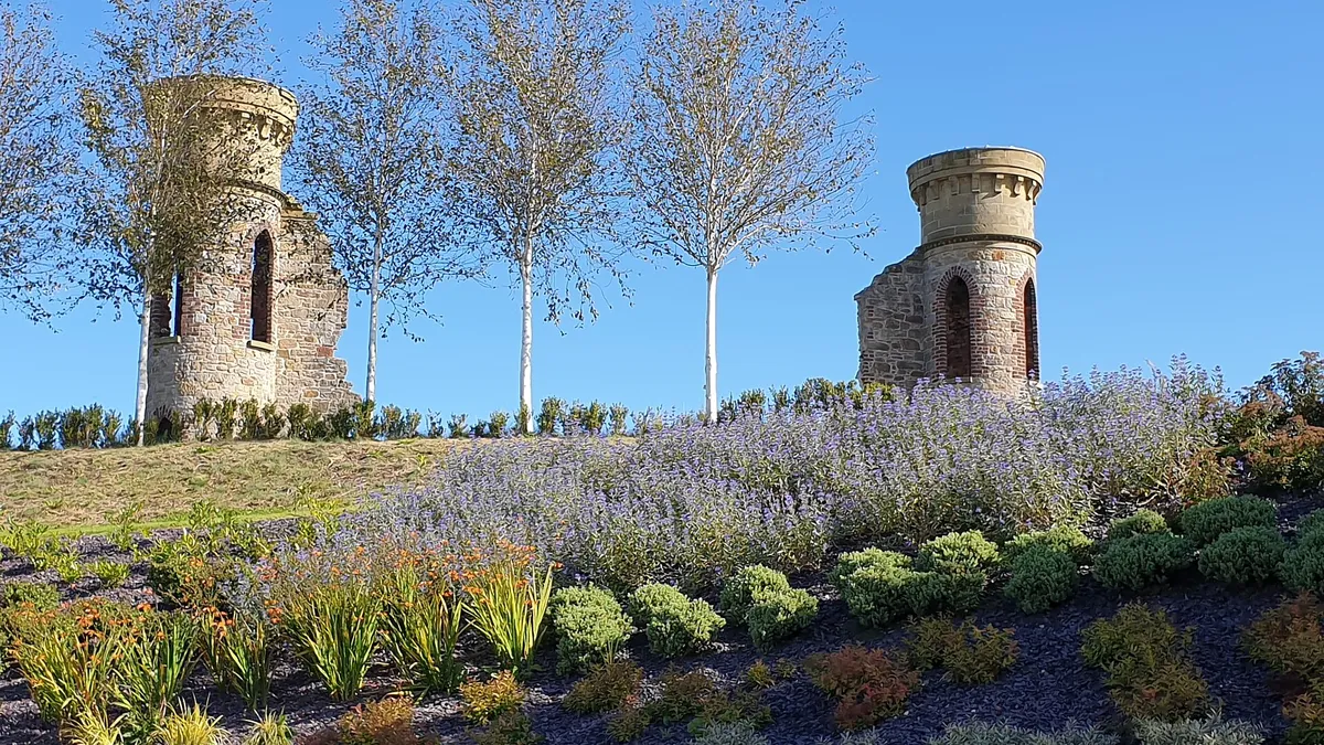 Two ruined stone turrets on top of the Hill of The O'Neill, with planted beds in front