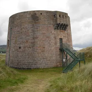 The squat round Martello tower at Magilligan Point among the dune grass, with an iron stair to its door