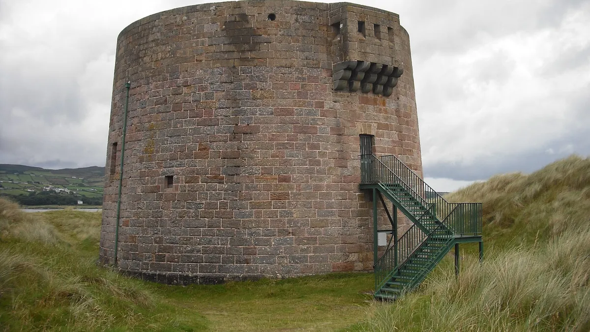 The squat round Martello tower at Magilligan Point among the dune grass, with an iron stair to its door