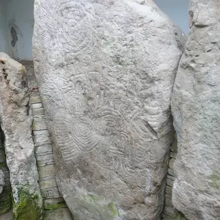 A tall chamber stone at Knockmany carved all over with faint circles and spirals
