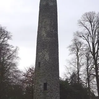 The stone shaft of Antrim Round Tower between bare trees
