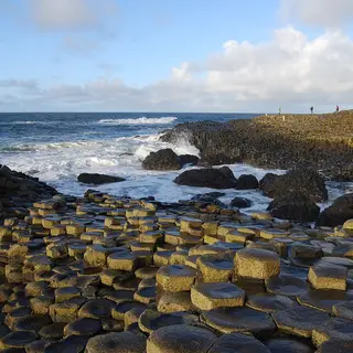 Basalt columns of the Giant's Causeway stepping down into a rough sea under a blue sky