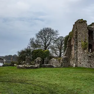 The ruined walls of the old castle at Crom on a lawn with Upper Lough Erne beyond