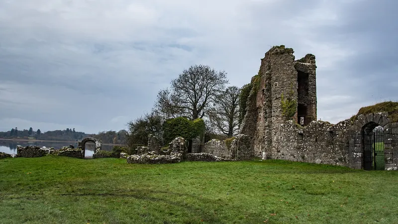 The ruined walls of the old castle at Crom on a lawn with Upper Lough Erne beyond