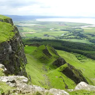 The basalt cliff edge of Binevenagh looking down over green farmland towards Lough Foyle