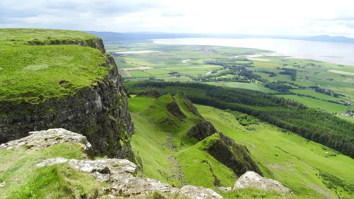 The basalt cliff edge of Binevenagh looking down over green farmland towards Lough Foyle