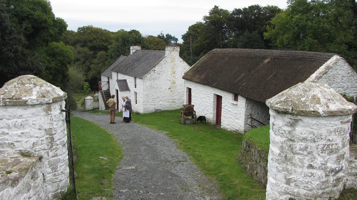 Whitewashed thatched farm buildings along a lane at the Ulster Folk Museum