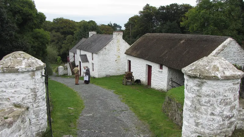 Whitewashed thatched farm buildings along a lane at the Ulster Folk Museum