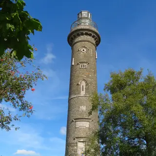 The tall stone column of the Spire of Lloyd seen through the branches of a tree