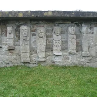 Eight carved stone figures set in a row into the wall of the ruined church on White Island