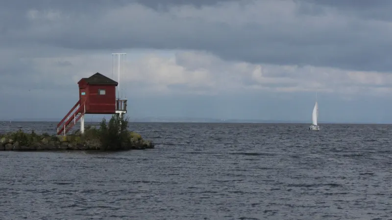 A red wooden lookout on a small jetty out in the grey water of Lough Neagh