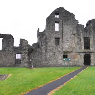 The gabled shell of Castle Balfour above a path through the graveyard at Lisnaskea