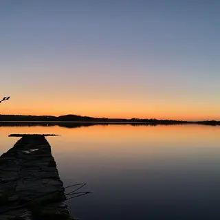 An old stone jetty running out into Lower Lough Erne under an orange evening sky