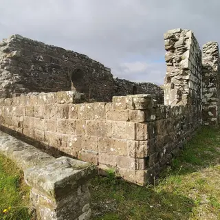 The roofless stone walls of Banagher Old Church standing in grass
