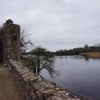 A ruined round tower of Portora Castle and the bawn wall running down to the River Erne