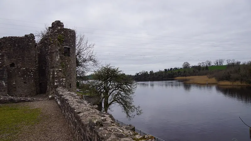 A ruined round tower of Portora Castle and the bawn wall running down to the River Erne