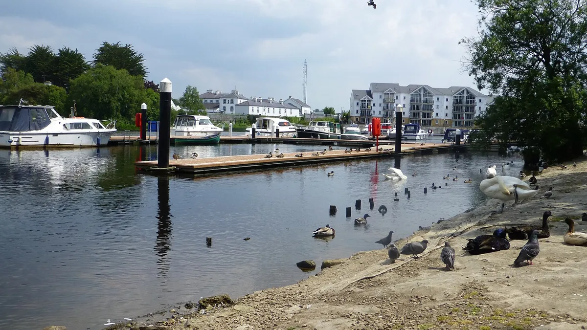 Boats moored at the Round O quay on the Erne in Enniskillen, with town buildings along the far bank