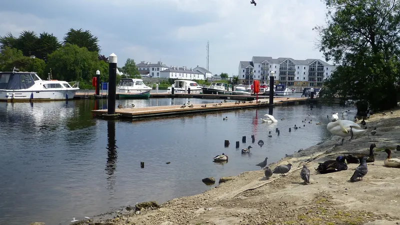 Boats moored at the Round O quay on the Erne in Enniskillen, with town buildings along the far bank