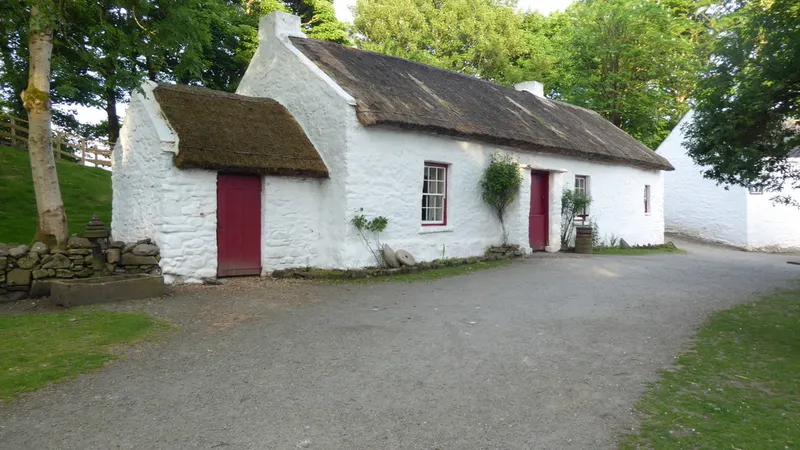 The whitewashed thatched Mellon homestead at the Ulster American Folk Park, with trees around it