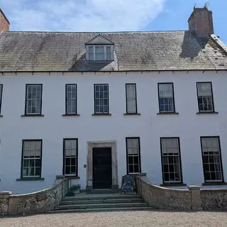 The whitewashed front of Springhill House with its steep slate roof and two chimneys