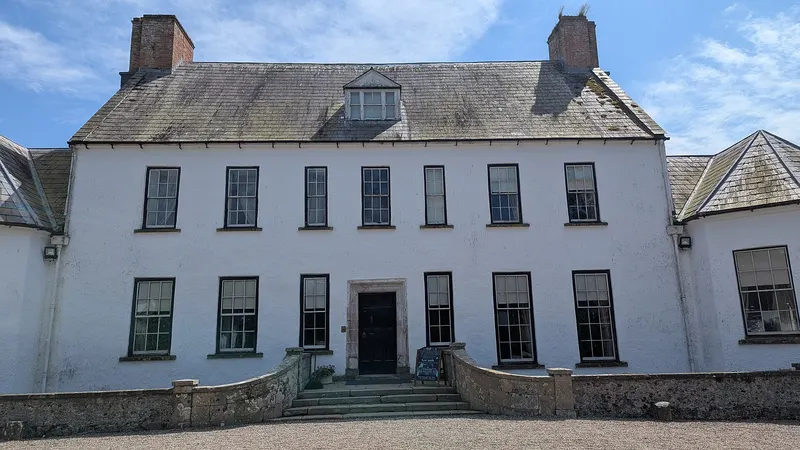 The whitewashed front of Springhill House with its steep slate roof and two chimneys