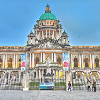 The front of Belfast City Hall with its green copper domes, seen across the grounds