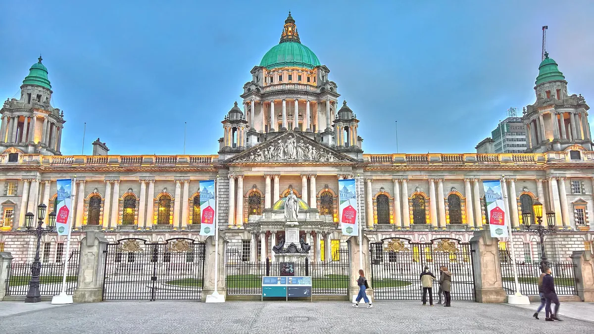 The front of Belfast City Hall with its green copper domes, seen across the grounds