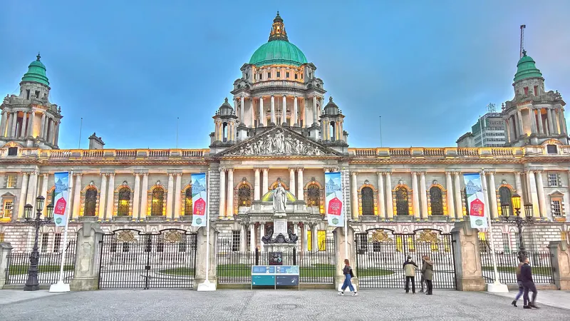 The front of Belfast City Hall with its green copper domes, seen across the grounds