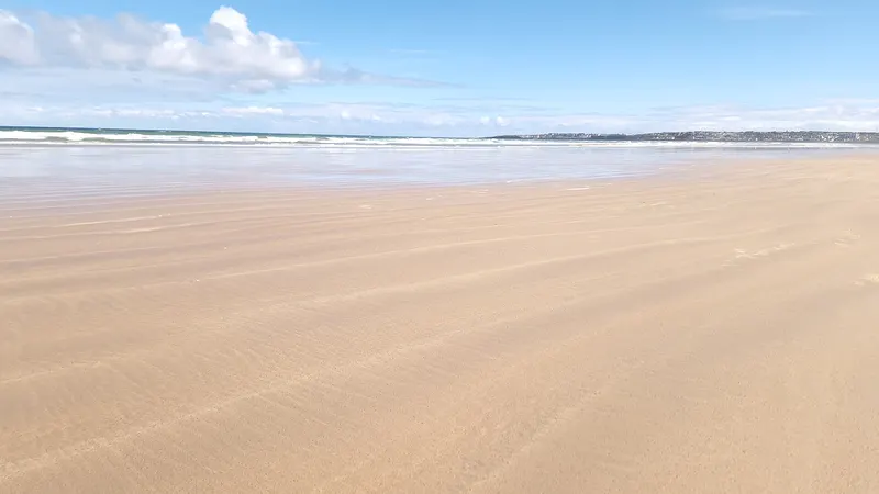 The wide, flat sand of Portstewart Strand under a clear sky