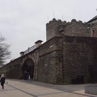 The battlemented stone tower of the Tower Museum rising behind the Magazine Gate in the city walls