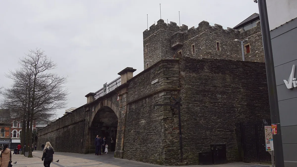 The battlemented stone tower of the Tower Museum rising behind the Magazine Gate in the city walls