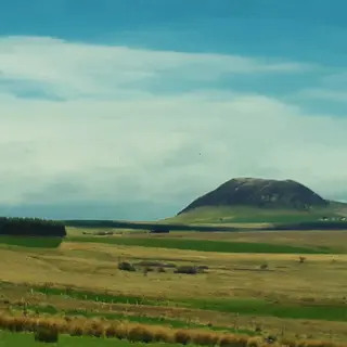 The rounded dark summit of Slemish standing alone above flat farmland