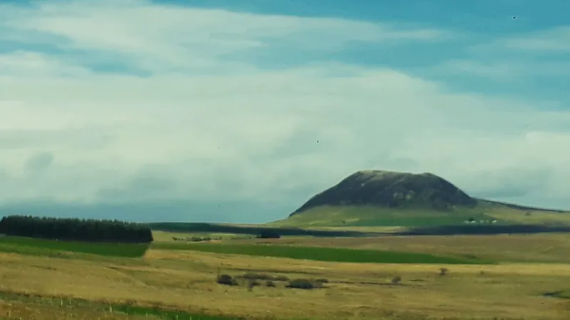 The rounded dark summit of Slemish standing alone above flat farmland