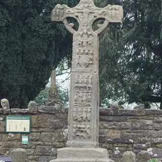The carved sandstone high cross at Donaghmore on its stepped base in front of a stone wall