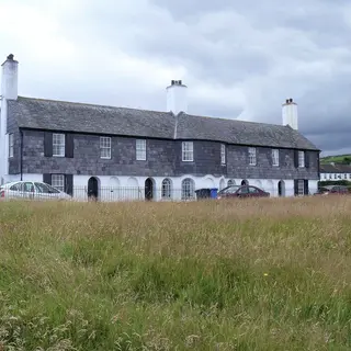 Maud Cottages in Cushendun, a slate hung terrace with white arches along the ground floor