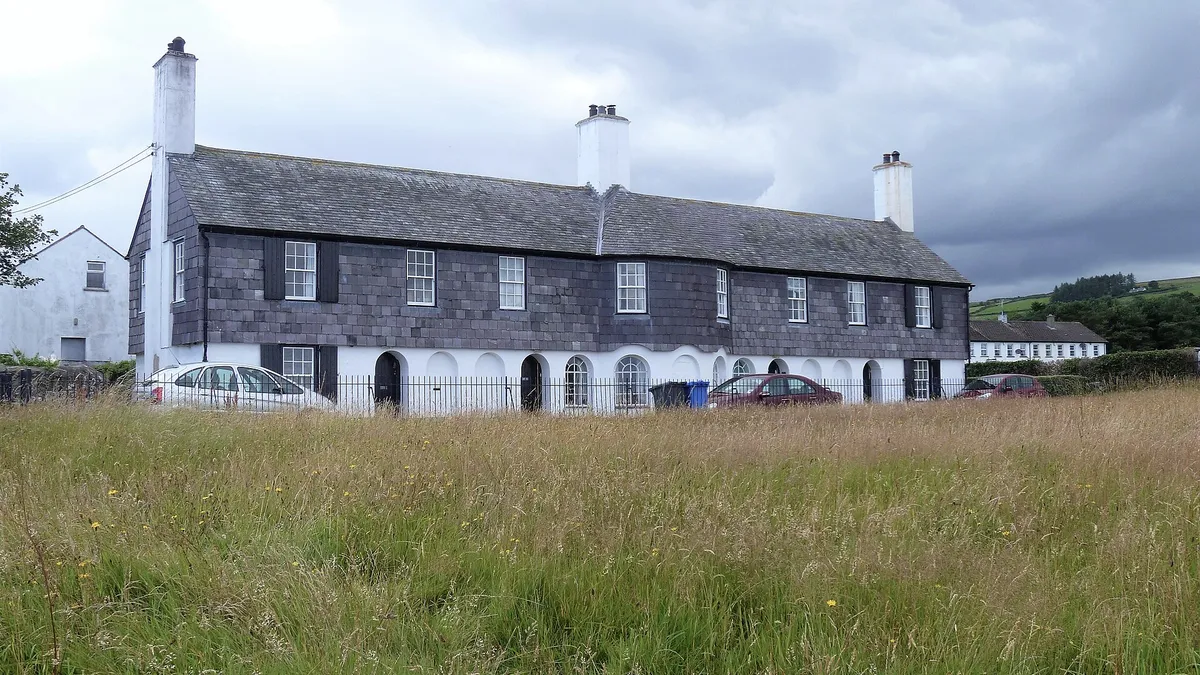 Maud Cottages in Cushendun, a slate hung terrace with white arches along the ground floor