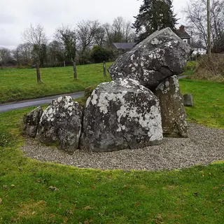 The sloping capstone of Tirnony Dolmen resting on its upright stones beside a country road