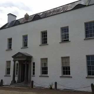 The long white front of Ardress House with a small pillared porch