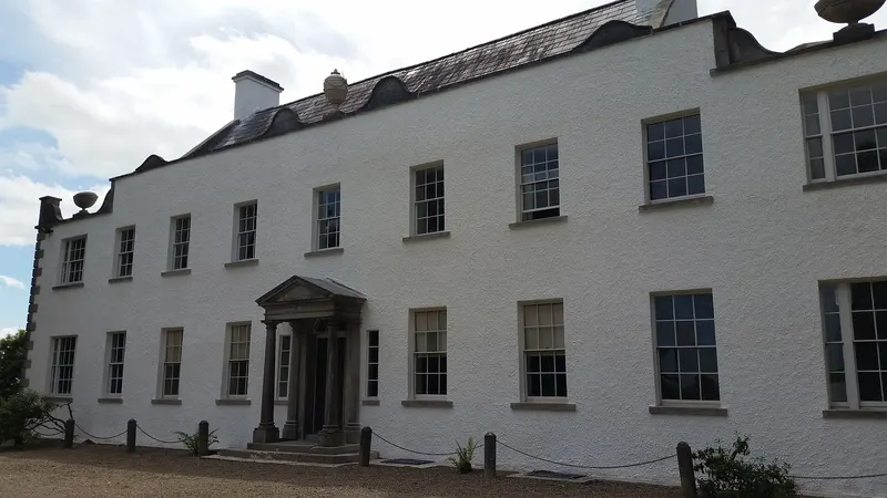 The long white front of Ardress House with a small pillared porch