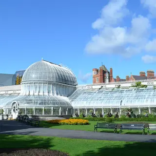 The curved glass Palm House in Botanic Gardens, Belfast, behind a lawn