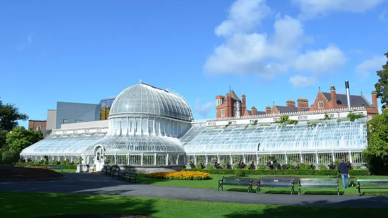 The curved glass Palm House in Botanic Gardens, Belfast, behind a lawn