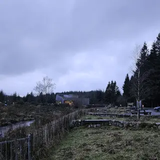 The OM observatory building at dusk in Davagh Forest, with a fenced path and conifers around it