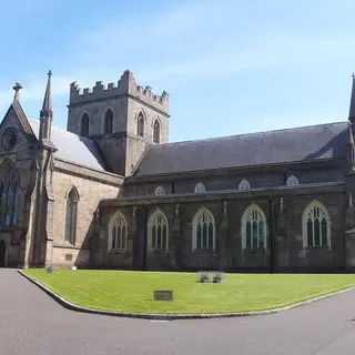 The sandstone Church of Ireland cathedral in Armagh with its square tower, behind a green lawn